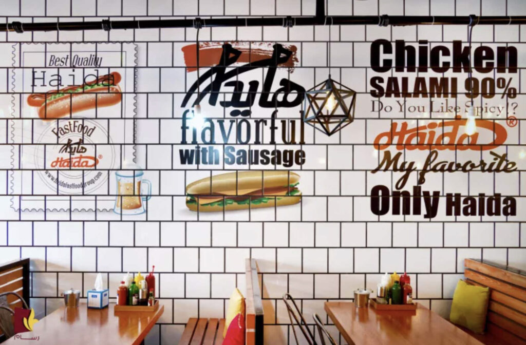 Image of a menu and branding message vertically printed on a ceramic tile wall in a sandwich shop